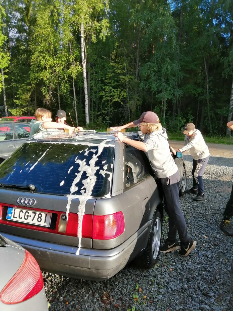 Pojat pesevät autoa, josta valuu saippuavettä.