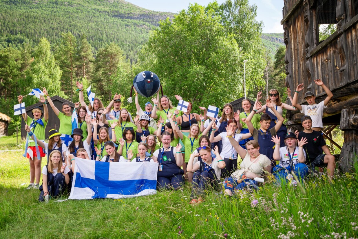 Joukko iloisia nuoria on esittelee Suomen lippua ja on somistautunut lipun väreihin.